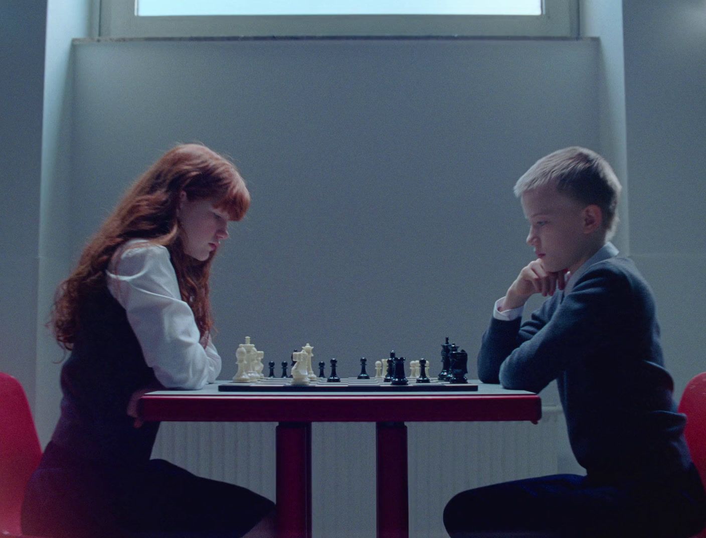 a boy and a girl playing a game of chess