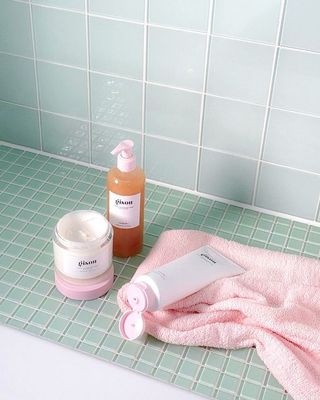 a pink towel sitting on top of a bath tub next to a bottle of lot