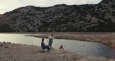 a group of people sitting on the shore of a lake