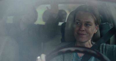a woman sitting in a car with a steering wheel
