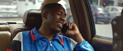 a man sitting in a car talking on a cell phone