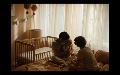 a man holding a baby while sitting on a bed