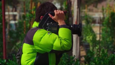 a man in a green jacket holding a camera