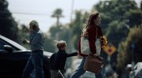 a woman and two children crossing the street