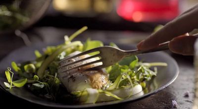 a person is holding a fork over a plate of food