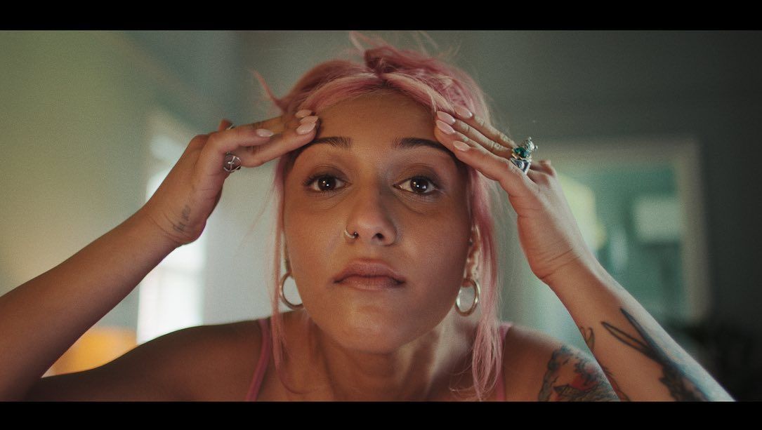 a woman with pink hair and piercings on her ears