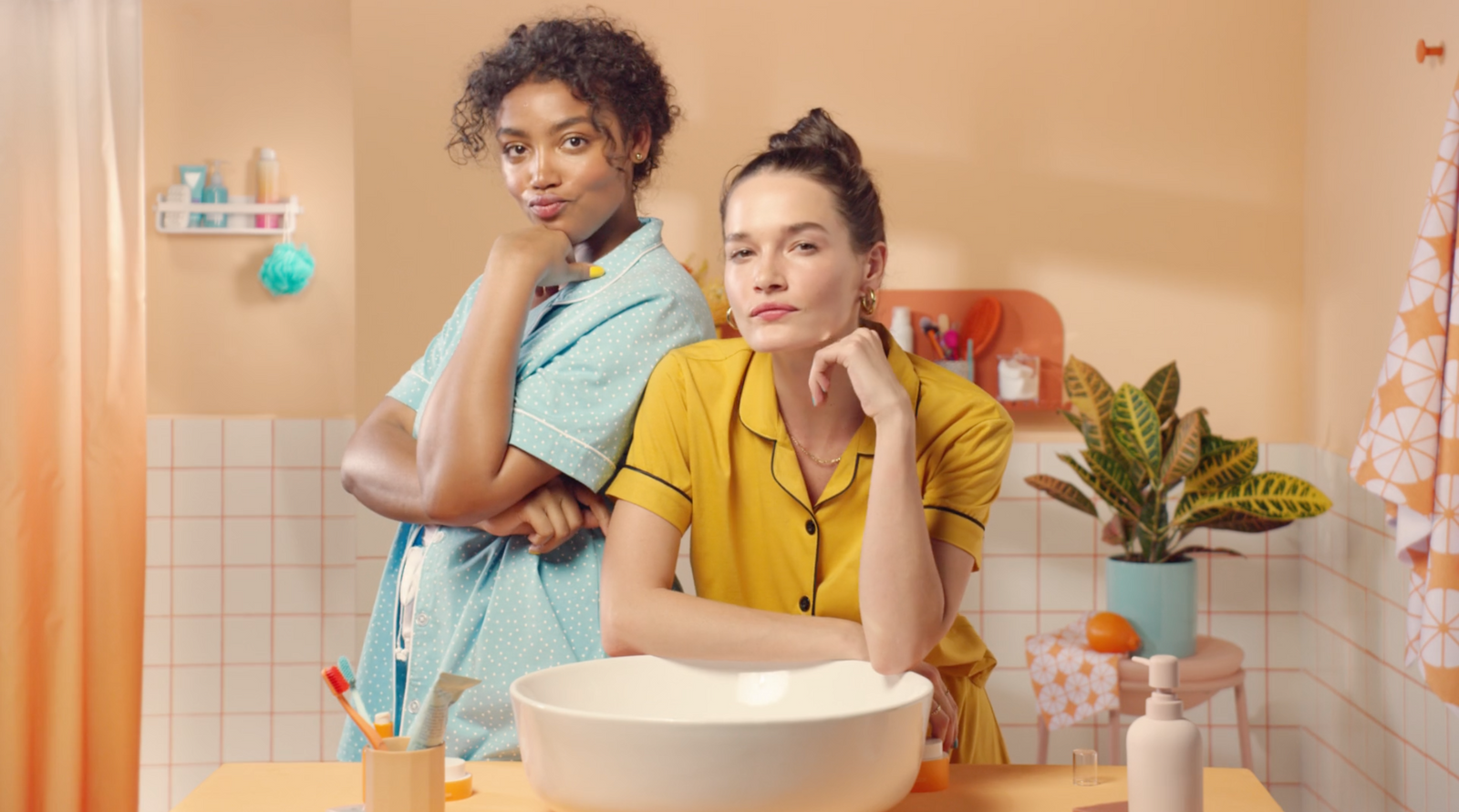 a couple of women standing in a bathroom next to a sink