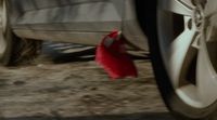 a red piece of cloth on the ground next to a car