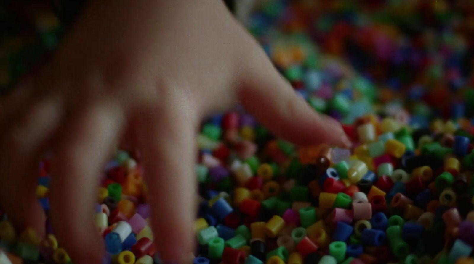 a hand reaching for a pile of beads