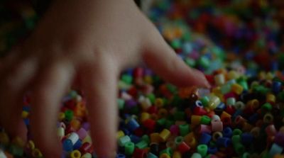a hand reaching for a pile of beads