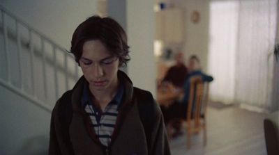 a young man standing in a hallway looking at his cell phone