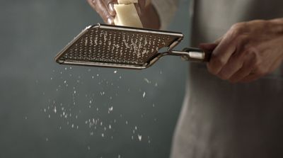 a person grating cheese with a grater