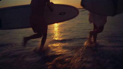 a couple of people walking across a beach holding surfboards