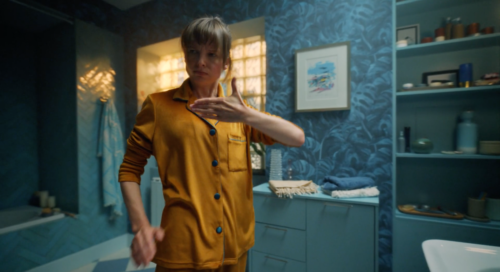 a woman in a yellow jumpsuit standing in a bathroom