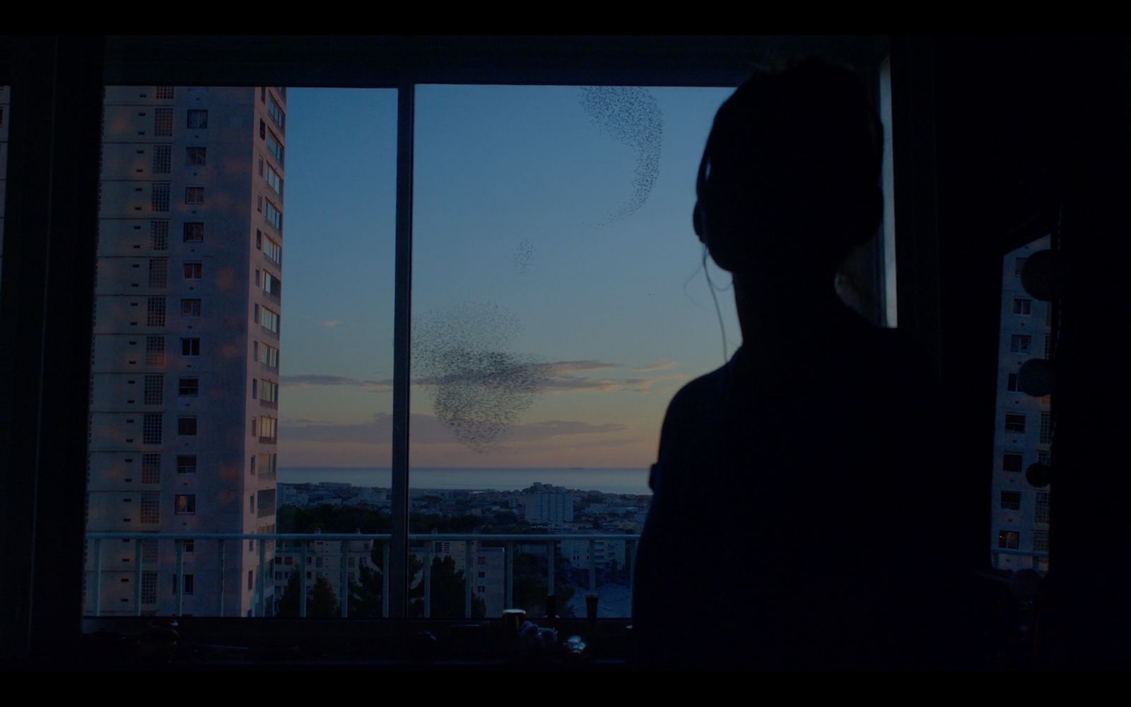 a woman looking out of a window at a sunset