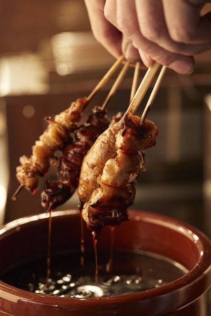 a person holding a skewer of food over a pot