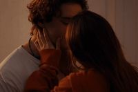 a man and a woman kissing in front of a mirror