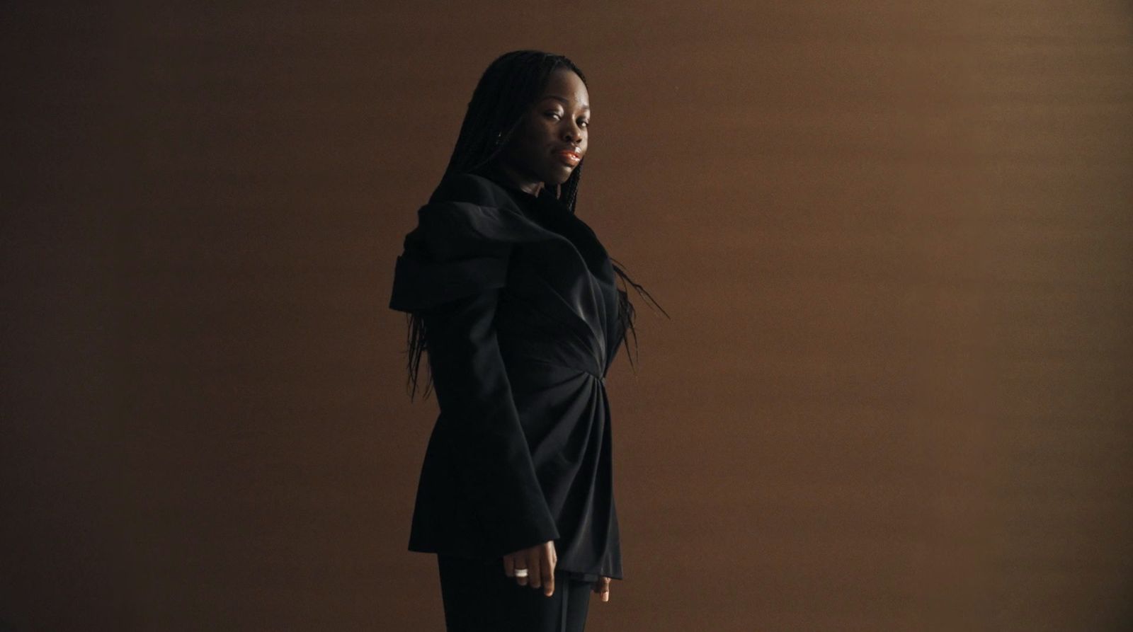 a woman standing in front of a brown wall