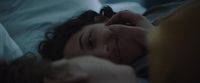 a woman laying in bed with her hand on her head