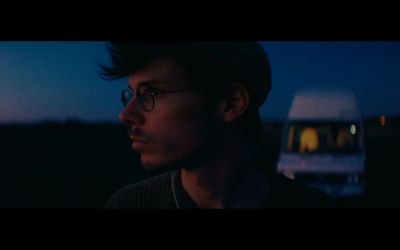 a man with glasses standing in front of a bus