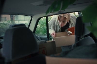 a woman opening a box in the back of a car