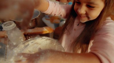 a little girl is making some food in a bowl