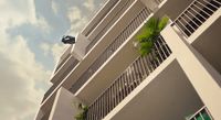 a tall white building with balconies and palm trees