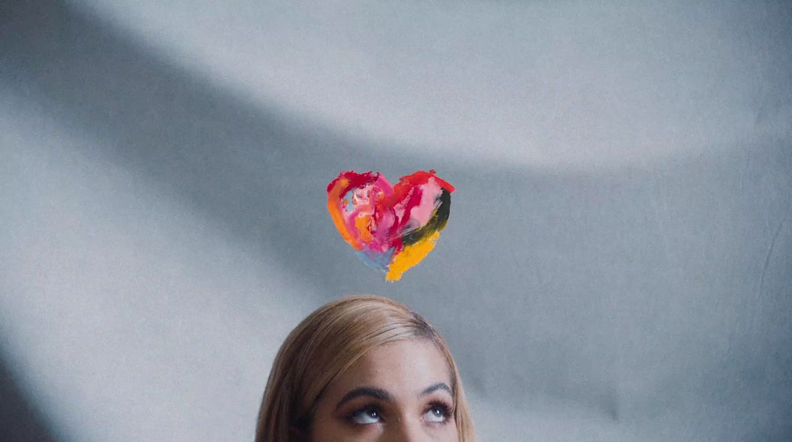 a woman looking up at a heart shaped piece of paper