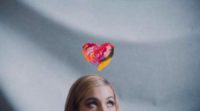 a woman looking up at a heart shaped piece of paper