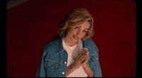 a woman in a jean jacket is posing for a picture