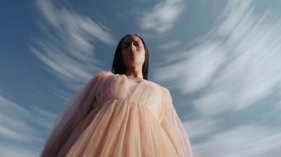 a woman in a dress looking up into the sky