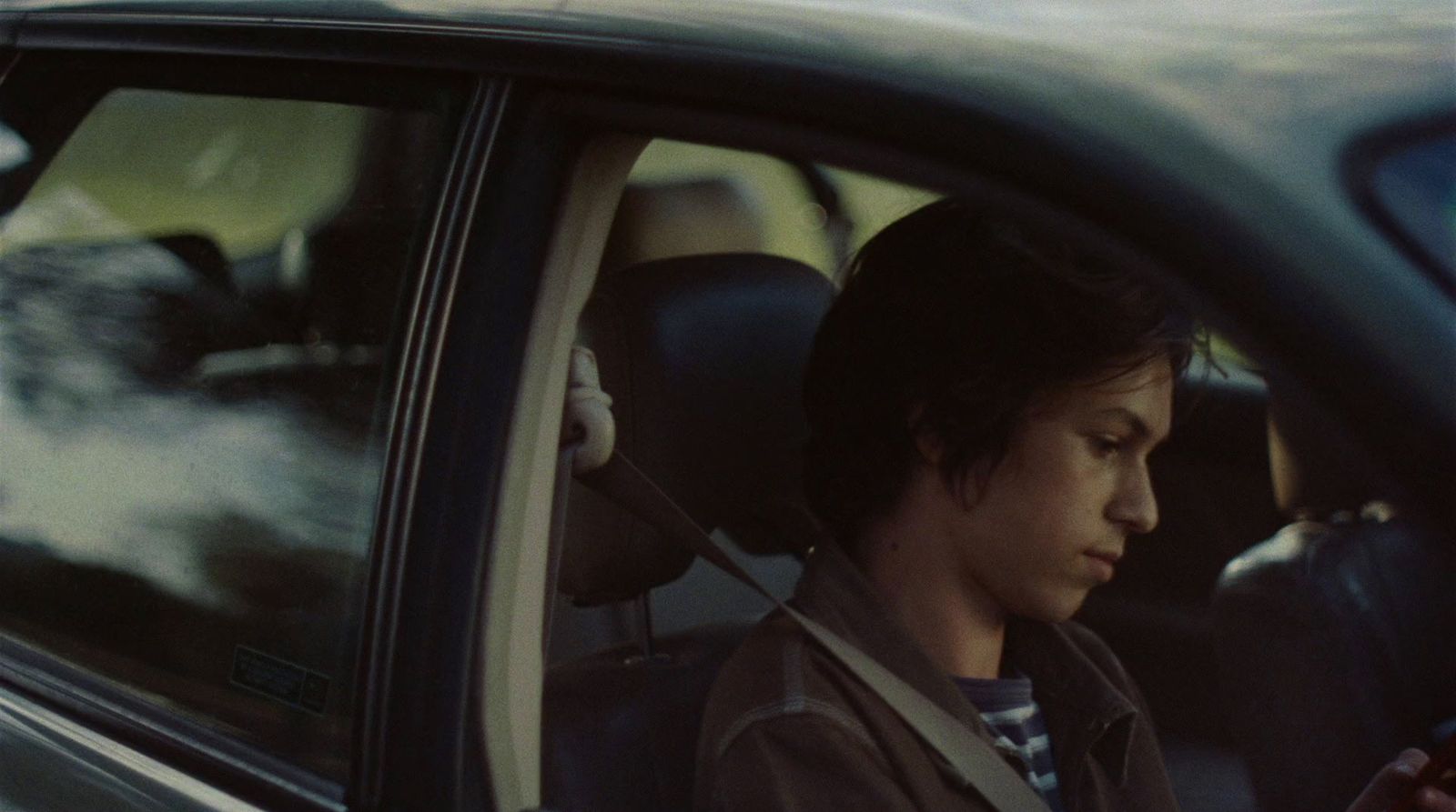 a man sitting in a car using a cell phone