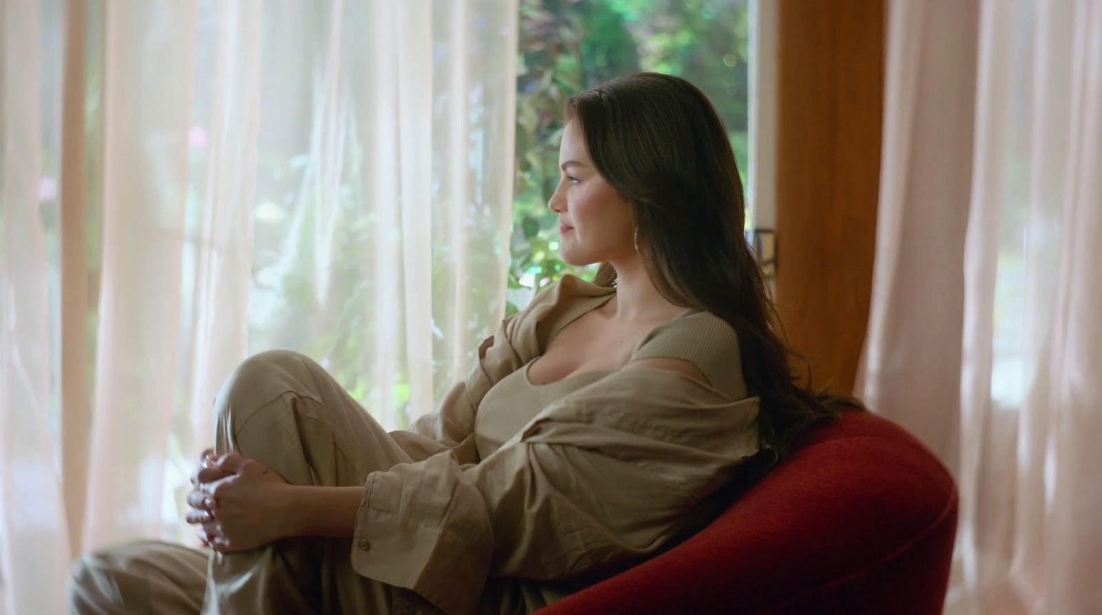 a woman sitting on a red chair in front of a window