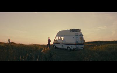 a man standing in a field next to an rv