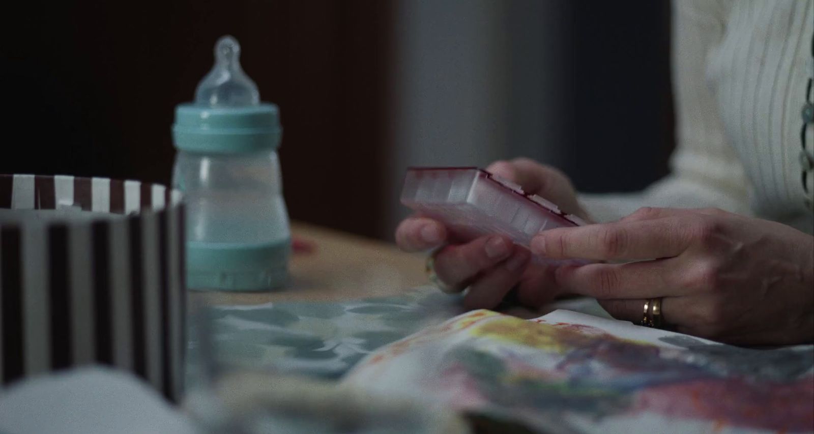 a woman sitting at a table with a baby bottle