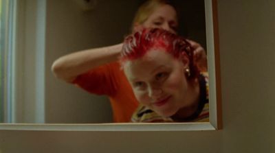 a woman is blow drying her hair in the mirror