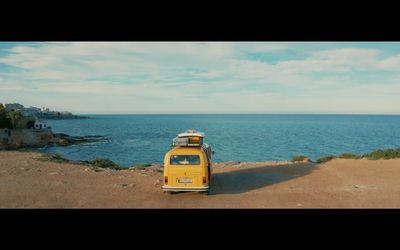 a yellow van parked on the side of a road next to the ocean