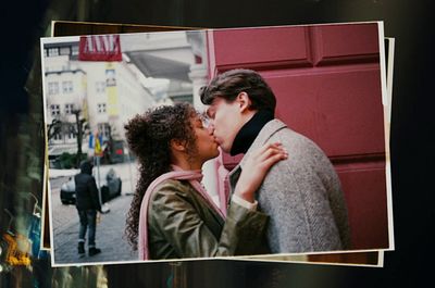 a man and a woman kissing in front of a red door