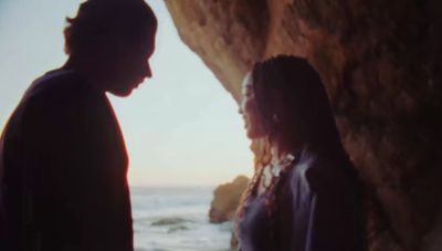 a man and a woman standing next to each other near the ocean