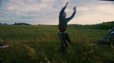 a man standing in a field reaching up to catch a frisbee