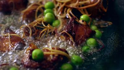 a frying pan filled with meat and peas