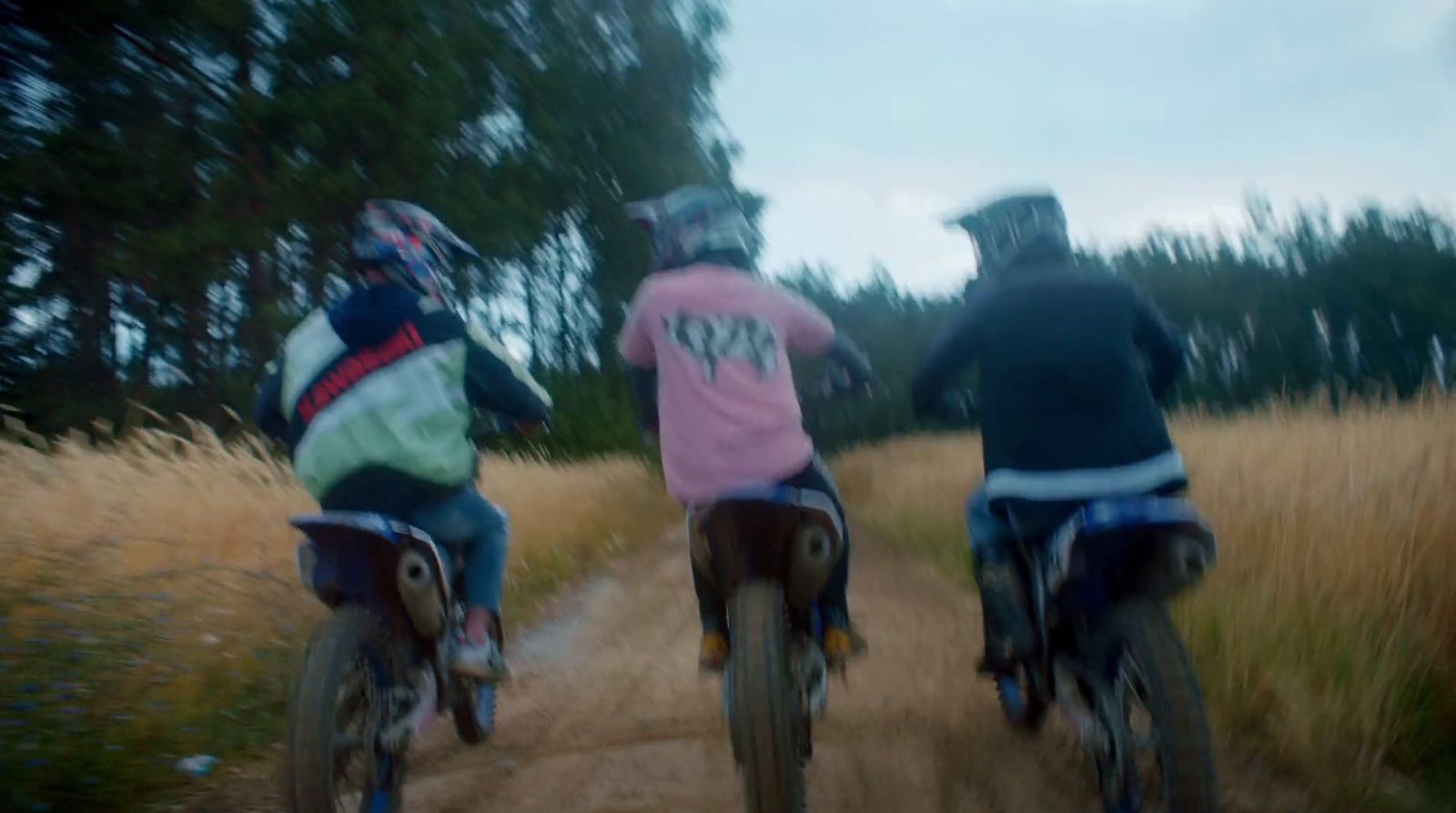 a couple of people riding bikes down a dirt road