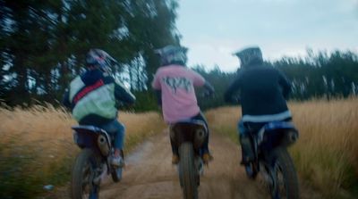 a couple of people riding bikes down a dirt road