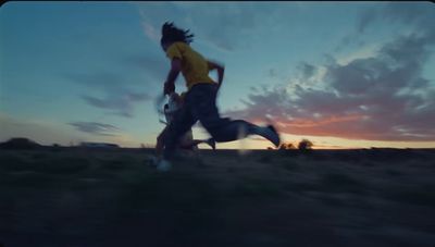 a man running through a field at sunset