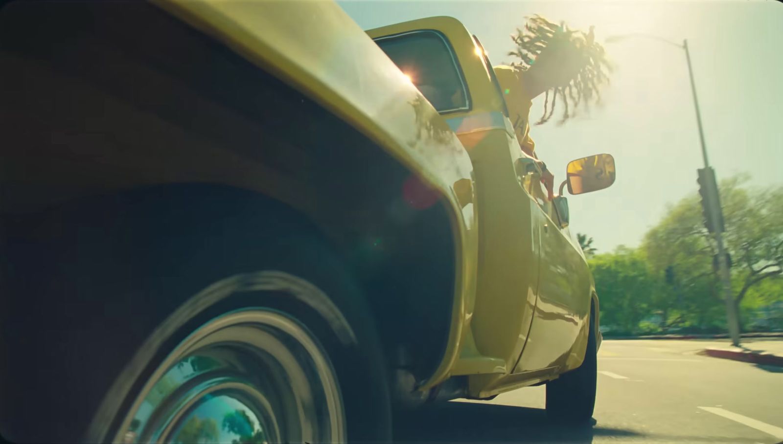 a yellow car driving down a street next to a traffic light