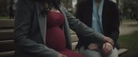 a pregnant woman sitting on a bench next to a man