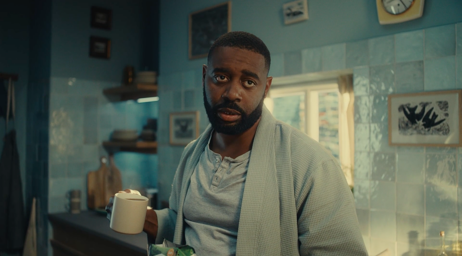 a man holding a cup of coffee in a kitchen