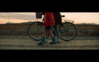 a person standing next to a bike on a dirt road