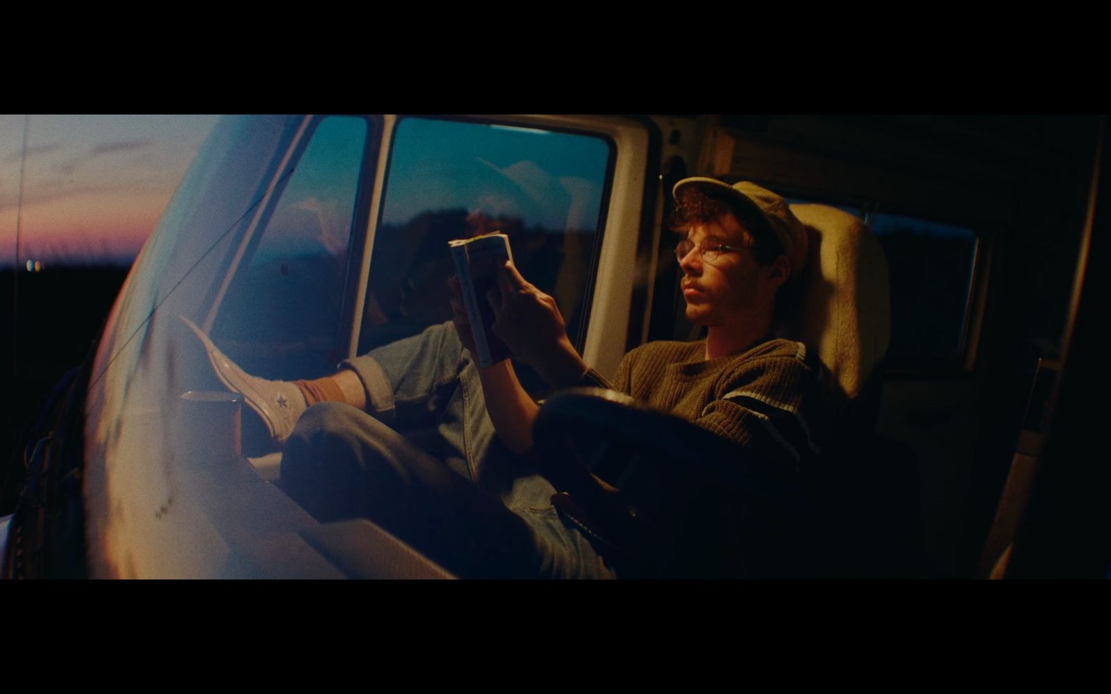 a man sitting in a car reading a book