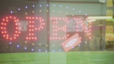 a neon sign in a store window that says open
